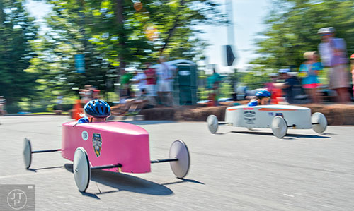 Jennifer Brown (left) speeds down her lane during the All American Dunwoody Soap Box Derby at the First Baptist Church of Atlanta in Dunwoody on Saturday, June 6, 2015. 