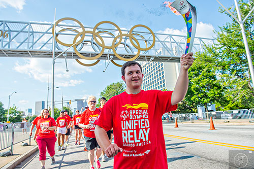 Will Crain (center), a special olympian from Hall County, carries the Flame of Hope down Hank Aaron Dr. and towards Turner Field in Atlanta during the Unified Relay Across America on Saturday, June 6, 2015. 