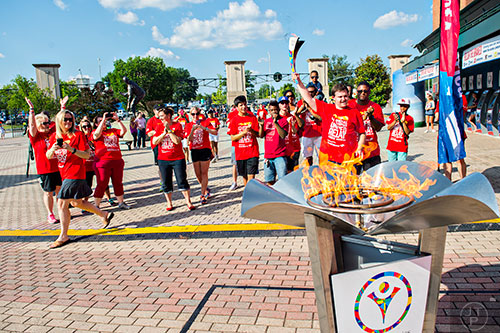 Will Crain (right), a special olympian from Hall County, lifts the Flame of Hope into the air after carrying it into Turner Field in Atlanta during the Unified Relay Across America on Saturday, June 6, 2015. 