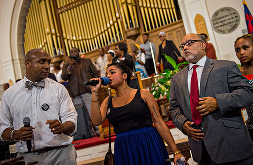 Mawuli Davis (left) and Sen. Vincent Fort (right) clap as Nelini Stamp sings during the Prayer, Healing and Reconciliation Service for members of the Emanuel A.M.E. Church in Charleston, South Carolina who lost their lives earlier this week at Big Bethel A.M.E. Church in Atlanta on Friday, June 19, 2015. 