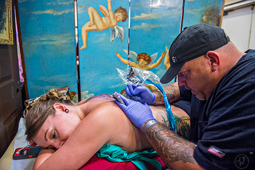 Chris Bowen (right) works on tattooing Justine Smith's back during the 19th annual Atlanta Tattoo Expo at the Wyndham Atlanta Galleria hotel on Saturday, June 20, 2015. 