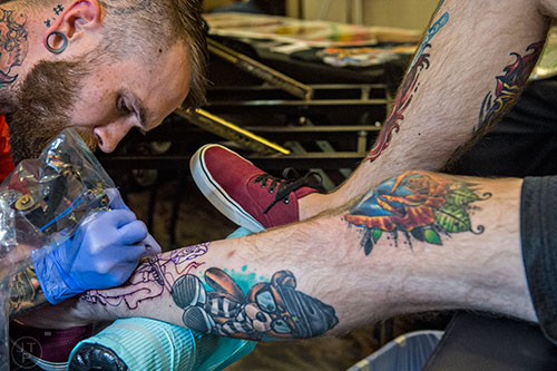 Mat Purdy (left) adds a fresh tattoo to Jake DeValk's collection on his legs during the 19th annual Atlanta Tattoo Expo at the Wyndham Atlanta Galleria hotel on Saturday, June 20, 2015. 