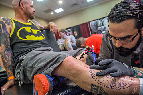 Matt Brumelow (right) works on a leg tattoo for Neil Guida during the 19th annual Atlanta Tattoo Expo at the Wyndham Atlanta Galleria hotel on Saturday, June 20, 2015. 