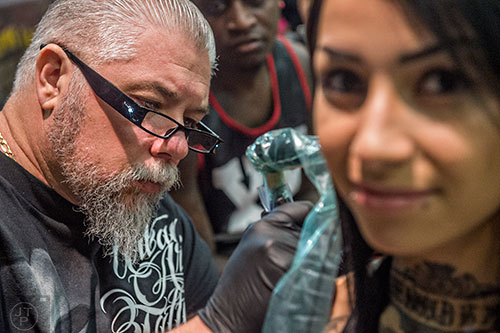 Sage O'Connell (left) works on tattooing Alison Briceno's arm during the 19th annual Atlanta Tattoo Expo at the Wyndham Atlanta Galleria hotel on Saturday, June 20, 2015. 