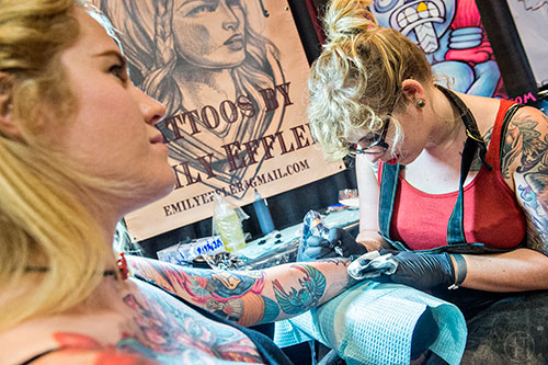 Emily Effler (right) works on a wrist tattoo for Glenna Kilgore during the 19th annual Atlanta Tattoo Expo at the Wyndham Atlanta Galleria hotel on Saturday, June 20, 2015. 