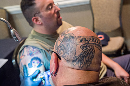 Brent Roman (center) tattoos Blake Sherman during the 19th annual Atlanta Tattoo Expo at the Wyndham Atlanta Galleria hotel on Saturday, June 20, 2015. 