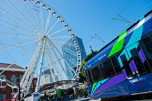 An Atlanta Streetcar passes under the SkyView Atlanta ferris wheel as it pulls out of the Centennial Olympic Park stop in downtown.