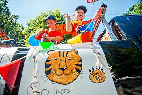 Teams with the Decatur Youth Baseball program ride in the back of trucks down East Lake Drive during a parade to celebrate opening day of the season on Saturday, June 6, 2015.