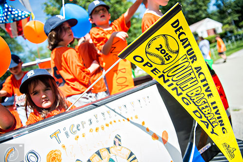Teams with the Decatur Youth Baseball program ride in the back of trucks down East Lake Drive during a parade to celebrate opening day of the season on Saturday, June 6, 2015.