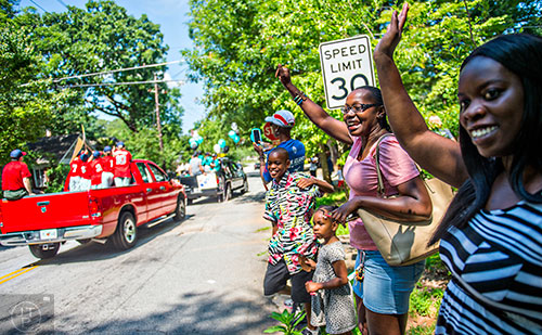 Jessica Smith (center) waves as teams with the Decatur Youth Baseball program ride in the back of trucks down East Lake Drive during a parade to celebrate opening day of the season on Saturday, June 6, 2015.