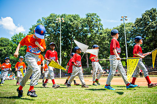 Teams with the Decatur Youth Baseball program walk out onto the field at Oakhurst Park for the opening day ceremony on Saturday, June 6, 2015.