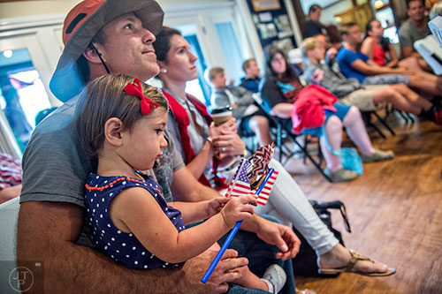 Pearl McDowell plays with a pinwheel and an American flag as she and her father J.R. listen to SmokeRise perform during the inaugural BBQ & Bluegrass at Barrington Hall in Roswell on Saturday, July 4, 2015. 