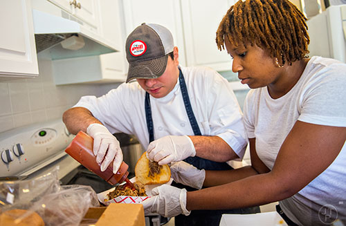 Mike Gambini (left) and Kristin Wornum prepare barbeque sandwiches during the inaugural BBQ & Bluegrass at Barrington Hall in Roswell on Saturday, July 4, 2015. 