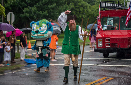 Jim Stacy (center) marches down Clarendon Ave. in the pouring rain during the Avondale Estates 4th of July Parade on Saturday, July 4, 2015. 