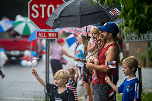 Justin Miller (right) holds his daughter Vera as they watch the Avondale Estates 4th of July Parade pass by on Saturday, July 4, 2015. 