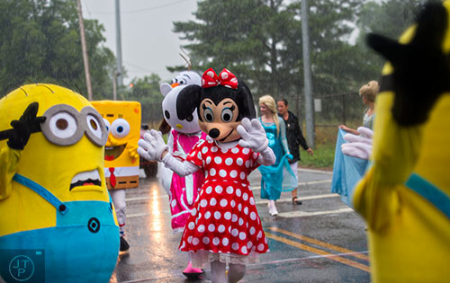 Disney characters like Minnie Mouse, Hello Kitty and some of the Minions march down Clarendon Ave. in the pouring rain during the Avondale Estates 4th of July Parade on Saturday, July 4, 2015. 