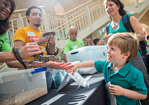 Thomas Gilbert (right) pets a ball python held by Michele Purcell during Reptile Day at the Fernbank Museum of Natural History in Atlanta on Saturday, July 11, 2015. 