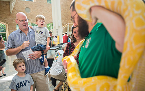Finn Brennan (left), his father Joe and brother Brooks check out a albino Burmese python held by John Lobello during Reptile Day at the Fernbank Museum of Natural History in Atlanta on Saturday, July 11, 2015. 