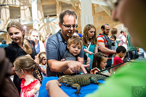 John Horback (center) holds his son John Jr. as they pet a rhino iguana during Reptile Day at the Fernbank Museum of Natural History in Atlanta on Saturday, July 11, 2015. 