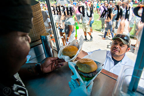 Tony Diaz (right) takes his burgers from Yaya Adkinson during the Atlanta Street Food Festival at Piedmont Park in Atlanta on Saturday, July 11, 2015. 