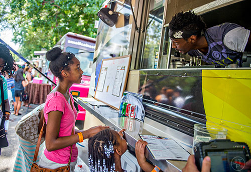 Ti'Yonna Keath (left) and her sister Shia order from Ricky Blake at the Genki food truck during the Atlanta Street Food Festival at Piedmont Park in Atlanta on Saturday, July 11, 2015.