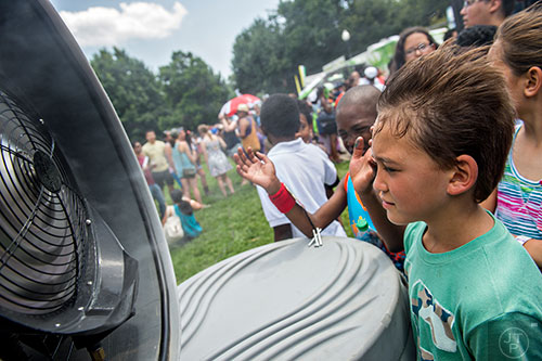 Gabriel Reque (right) and Joseph Edmond cool off in front of a water fan during the Atlanta Street Food Festival at Piedmont Park in Atlanta on Saturday, July 11, 2015. 