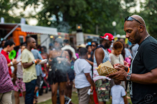 Ray Brodie (right) digs into his order from the Bento Box food truck during the Atlanta Street Food Festival at Piedmont Park in Atlanta on Saturday, July 11, 2015.