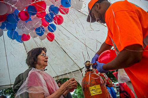 Mary Galpin (left) and Oscar Griffin blow up balloons before the start of the Avondale Estates 4th of July Parade on Saturday, July 4, 2015.  