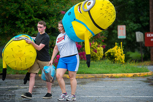 Brieson Cox (left) and Renee Davis carry minion costumes out of the rain before the start of the Avondale Estates 4th of July Parade on Saturday. 
