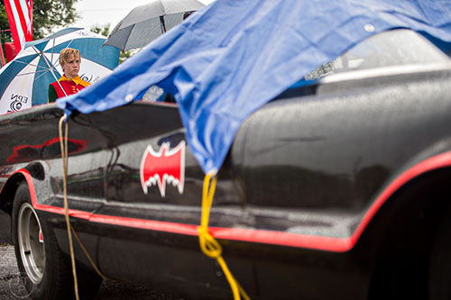 Dressed as Robin, J.J. Moran stands next to the Batmobile underneath an umbrella before the start of the Avondale Estates 4th of July Parade on Saturday.  