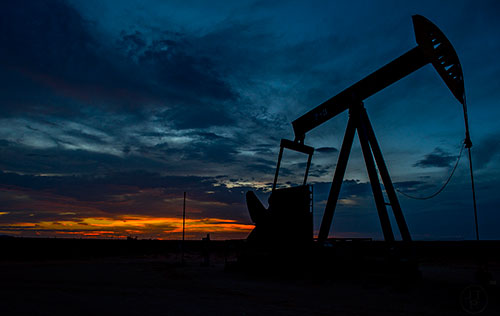 An oil rig rotates as the sun sets outside of Brownfield, Texas on Wednesday, July 15, 2015.