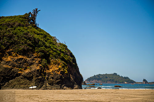 A lone surfer walks along the beach by Camel Back Rock in northern California on Thursday, July 23, 2015.