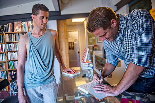 Author Jesse Goolsby (right) signs a copy of his book for Christian Bradley West at A Cappella bookstore in Atlanta on Monday, June 29, 2015. 