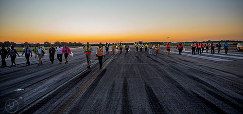 Around 100 airport employees walk down runway 8L/26R at Hartsfield Jackson Atlanta International Airport looking for foreign object debris during the 14th annual FOD Walk on Wednesday, August 26, 2015.  