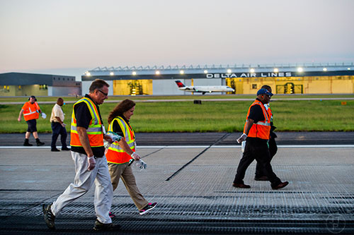 Tom Galusha (left) and Connie Davenport look for foreign object debris as they walk down runway 8L/26R at Hartsfield Jackson Atlanta International Airport during the 14th annual FOD Walk on Wednesday, August 26, 2015. 