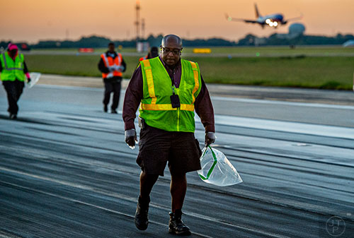 Denver Pollard (center) looks for foreign object debris as he and other airport employees walk down runway 8L/26R at Hartsfield Jackson Atlanta International Airport during the 14th annual FOD Walk on Wednesday, August 26, 2015. 