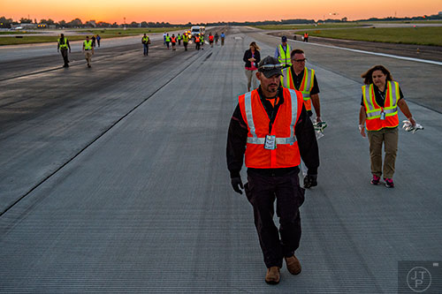 Josh Miller (center) looks for foreign object debris as he and other airport employees walk down runway 8L/26R at Hartsfield Jackson Atlanta International Airport during the 14th annual FOD Walk on Wednesday, August 26, 2015. 