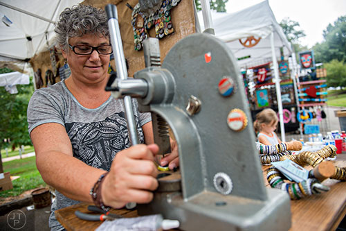 Artist Donna DiGiorgio presses holes into caps at her booth during the 13th annual Grant Park Summer Shade Festival on Saturday, August 29, 2015. 