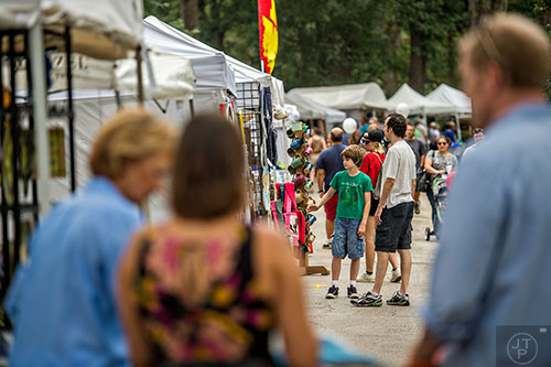 Gordon Eilen (center) and his son Alex walk by the rows of artist booths  during the 13th annual Grant Park Summer Shade Festival on Saturday, August 29, 2015. 