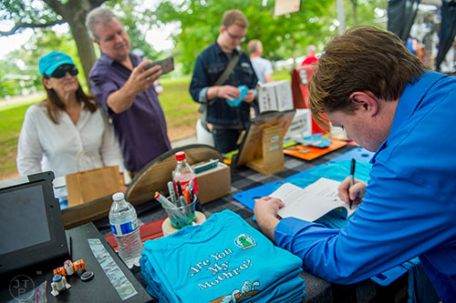 Artist Jason Albin Thomas (right) signs a book for Lee and Steve Fincher's grandson during the 13th annual Grant Park Summer Shade Festival on Saturday, August 29, 2015. 