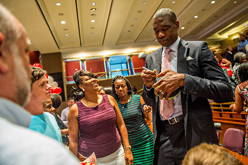 Dikembe Mutombo (right) signs autographs after the celebration naming September 1 as Dikembe Mutombo Day in Fulton County at the Fulton County Government Center in Atlanta on Tuesday, September 1, 2015.   