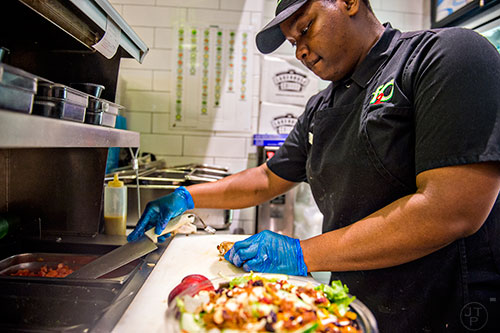 Alfred Ward reaches for a tethered knife to slice chicken for a salad at Fresh to Order inside the Hartsfield Jackson Atlanta International Airport on Wednesday, September 2, 2015. 