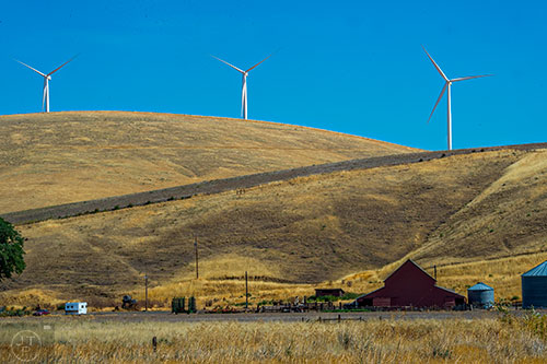 Wind turbines turn on the hillside above a farm in Washington state on Wednesday, August 5, 2015.