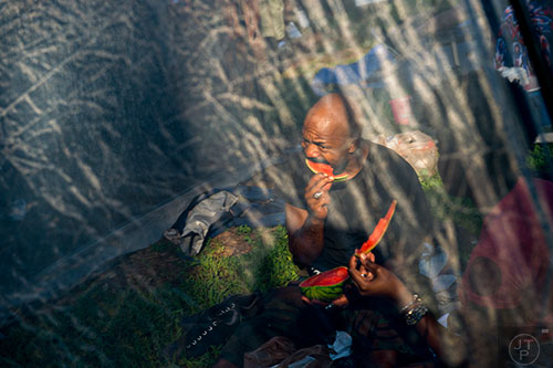 Mike Frazier eats a slice of watermelon while staying away from the bugs in his tent during House at the Park at Grant Park in Atlanta on Sunday, September 6, 2015.