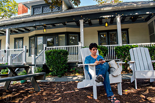 Maria Riley sits in an adirondack chair outside of Revival in Decatur as she waits on the rest of her party to arrive.