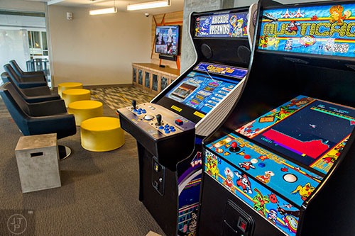 The upper level of the community room inside University House in Atlanta features arcade games, console games with large screen televisions and a view of the outdoor courtyard and pool.