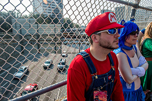 Chris Kroner (left) and Kate Powell lean against an interstate overpass as they wait on Peachtree St. in Atlanta for the annual DragonCon Parade to start on Saturday, September 5, 2015.   