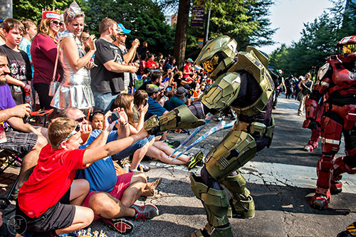 Dressed as Master Chief from the HALO series, Justin Branfuhr (center) gives a fist bump to Aidan Meehan as he marches down Peachtree St. during the annual DragonCon Parade in Atlanta on Saturday, September 5, 2015.  