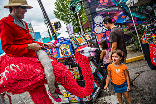 Tony Schott (left) rides up to Maya Rosenkoetter on his flamingo during the 5 Arts Fest in the Little Five Points neighborhood of Atlanta on Saturday, September 12, 2015. 
