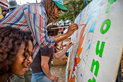 Amina Person (center) helps fill in the community mural with paint during the 5 Arts Fest in the Little Five Points neighborhood of Atlanta on Saturday, September 12, 2015.